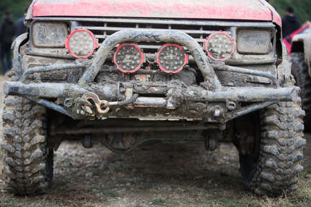Close up shot of an off road car front, covered in mud, with bullbar and headlights.