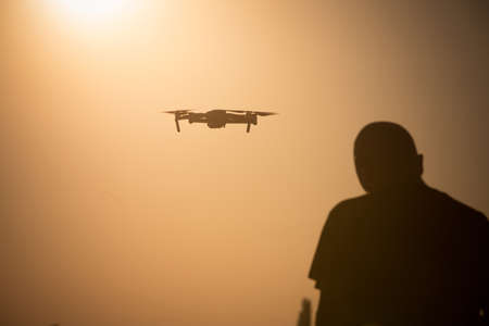 Color image of a man flying a drone at sunrise.の写真素材