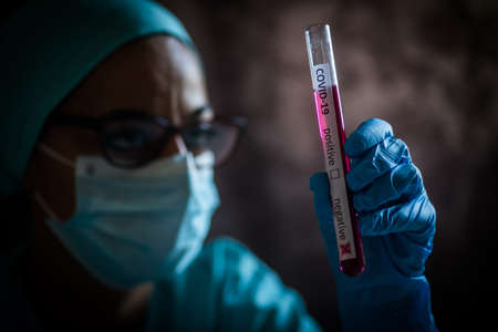 Conceptual photograph of a doctor's hands holding and looking at a test tube while with negative...