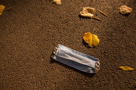 Close up shot of a used surgical mask, lying on the ground, illustration for the Covid-19 pandemic.の写真素材