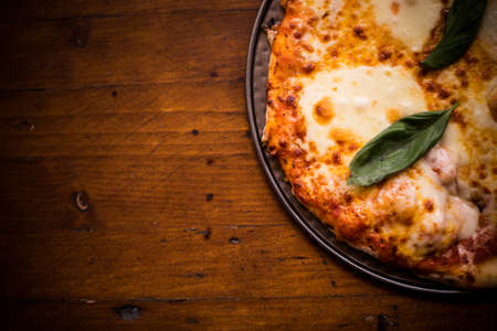 Close up shot of a pizza on a wooden table.