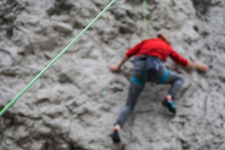 Close up shot of a green rock climbing rope, with a blurred climber in the background.の写真素材