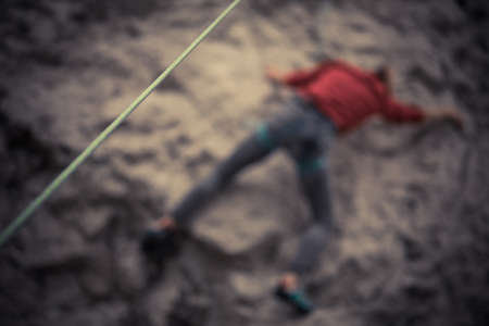 Close up shot of a green rock climbing rope, with a blurred climber in the background.の写真素材