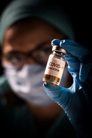 Image of a female doctor holding a COVID-19 vaccine, illustration for the new coronavirus pandemic.
