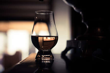 Color close up shot of a Glencairn whisky glass on a wooden table, with shallow depth of field.の写真素材