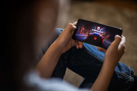 Bucharest, ROMANIA - May 10, 2021: Illustrative editorial concept image of a child playing Asphalt 9...
