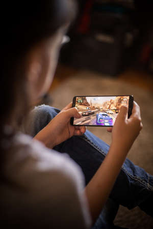 Bucharest, ROMANIA - May 10, 2021: Illustrative editorial concept image of a child playing Asphalt 9 racing game on a mobile phone.のeditorial素材