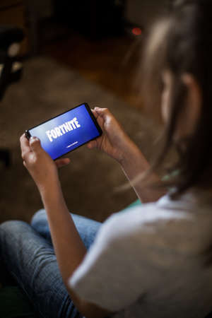 Bucharest, ROMANIA - May 10, 2021: Illustrative editorial concept image of a child playing Fortnite game on a mobile phone. Fortnite is a multiplayer Battle Royale shooter game by Epic Games.のeditorial素材