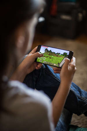 Bucharest, ROMANIA - May 10, 2021: Illustrative editorial concept image of a child playing Minecraft game on a mobile phone.のeditorial素材