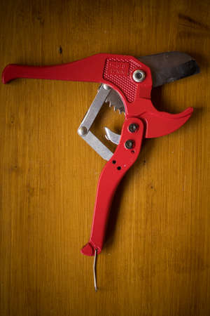 Close up shot of a PVC pipe cutter tool on a wooden background.の写真素材