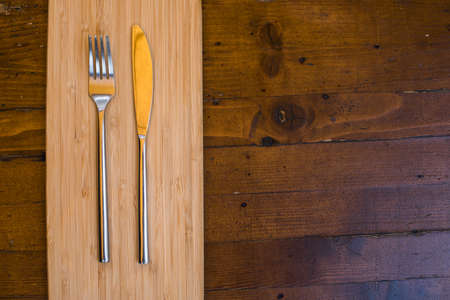 A shiny knife and fork on a wooden table.の写真素材