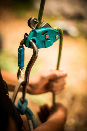 Close up shot of a man's hands operating a rock climbing assisted belaying device.の写真素材