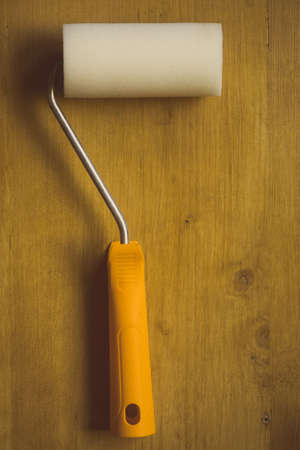 Close up shot of a paint roller on a wooden background.の写真素材