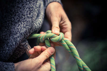 Detail with a climber's hands tying a figure eight know to the harness.の写真素材
