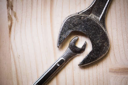 Close up shot of two metal wrenches on a wooden background.