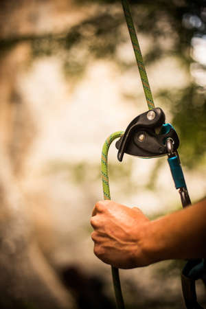 Close up shot of a man's hands operating a rock climbing assisted belaying device.