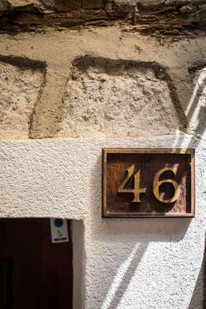 Number 46 plaque on a dirty old house wall.