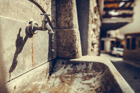 Old stylized vintage bronze faucet on the public street.の写真素材