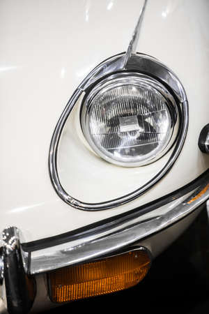 Closeup shot of the turn signal and headlight of a retro white car.