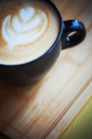 Hot cappuccino in a cup, placed on a wooden tray in retro coffee shop.の写真素材
