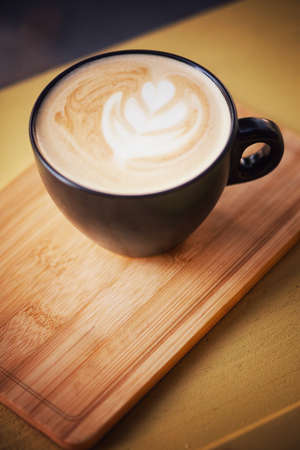 Hot cappuccino in a cup, placed on a wooden tray in retro coffee shop.の写真素材