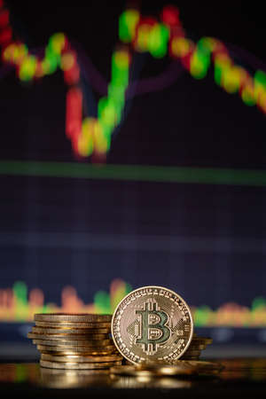 Stack or heap of gold Bitcoins cryptocurrency with candle stick graph chart and digital background.