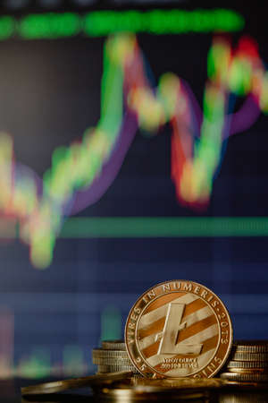 Stack or heap of gold Litecoin cryptocurrency with candle stick graph chart and digital background.