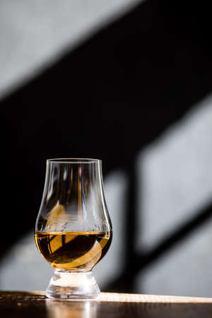 Image of a Glencairn single malt whisky glass, with light and shadows in the background.の写真素材