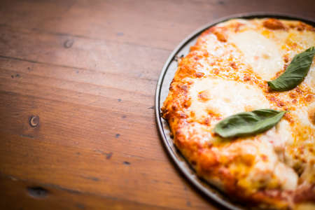Close up shot of a pizza on a wooden table, with copy space.の写真素材