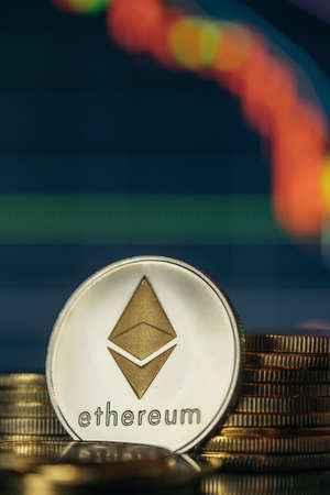 Stack or heap of silver Ethereum cryptocurrency with candle stick graph chart and digital background.の写真素材