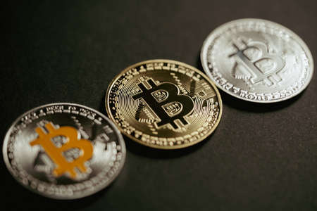 Close up shot of three aligned golden and silver bitcoin digital cryptocurrency.