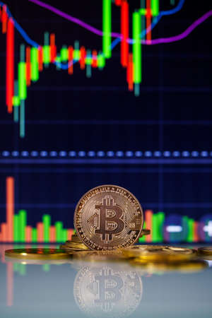 Stack or heap of gold Bitcoins cryptocurrency with candle stick graph chart and digital background.