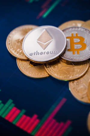 Stack or heap of gold various cryptocurrency coins with candle stick graph chart and digital...