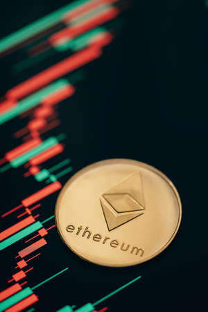 Gold Ethereum cryptocurrency coin with candle stick graph chart and digital background.の写真素材