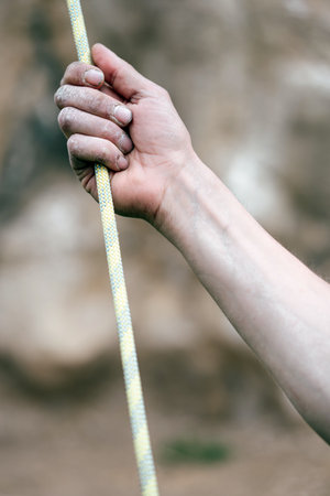 Color close up of a human hand holding a rock climbing rope.