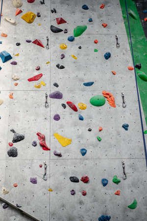 Close up photo of a rock climbing wall with climbing holds in gym.の写真素材