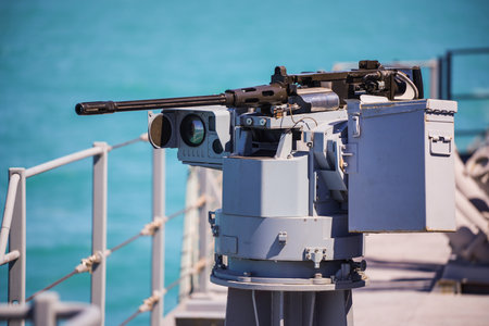 Color image of an automated machine gun on the deck of a military ship, at sea.