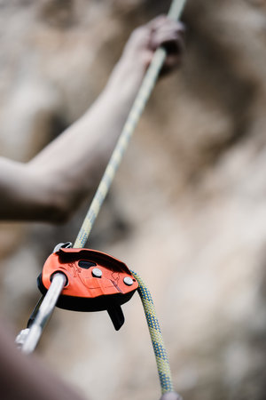 Close up shot of a man's hands operating a rock climbing assisted belaying device.