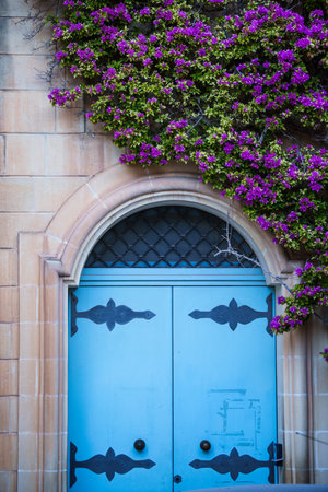 Old cozy house entrance with wooden door and colorful flowers.の写真素材