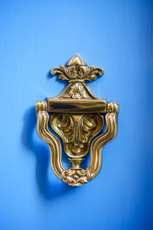 Close up color image of a vintage metal knocker on a wooden door.