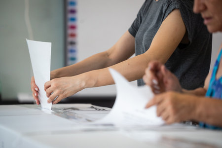 A person inserts a ballot in a box while voting at a polling station during elections.の写真素材
