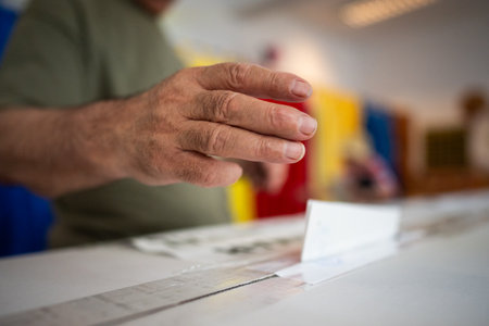 A person inserts a ballot in a box while voting at a polling station during elections.
