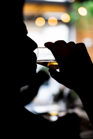 Silhouette of a person holding a Glencairn single malt whisky glass.の写真素材