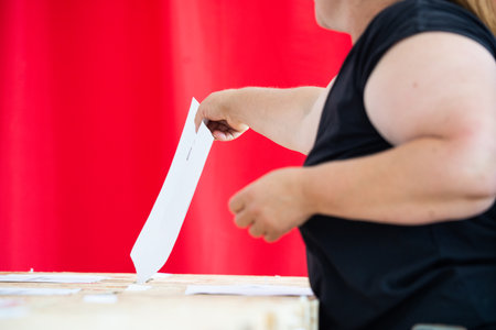 A person inserts a ballot in a box while voting at a polling station during elections.