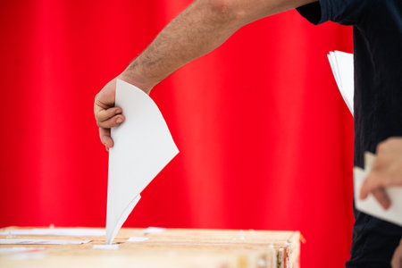 A person inserts a ballot in a box while voting at a polling station during elections.