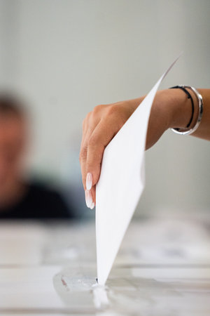 A person inserts a ballot in a box while voting at a polling station during elections.