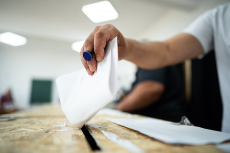 A person inserts a ballot in a box while voting at a polling station during elections.
