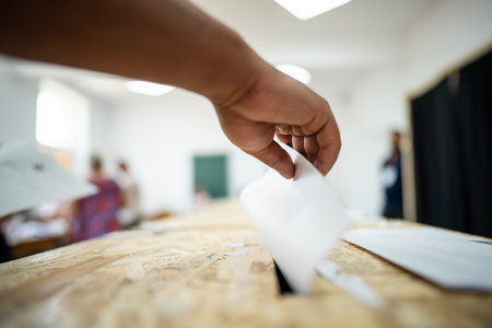 A person inserts a ballot in a box while voting at a polling station during elections.