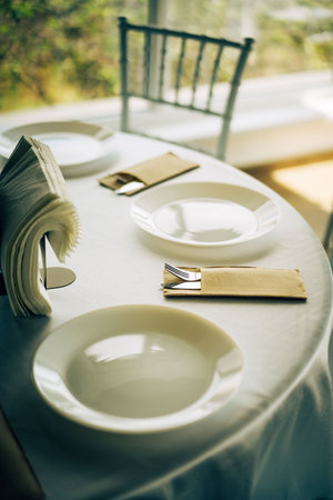 Romantic restaurant table setting with white plate and cutlery.の写真素材
