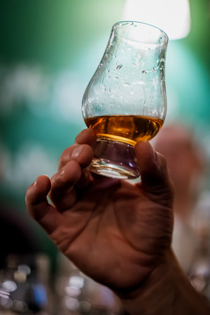 Color close up shot of a hand holding a single malt Glencairn whisky glass.の写真素材